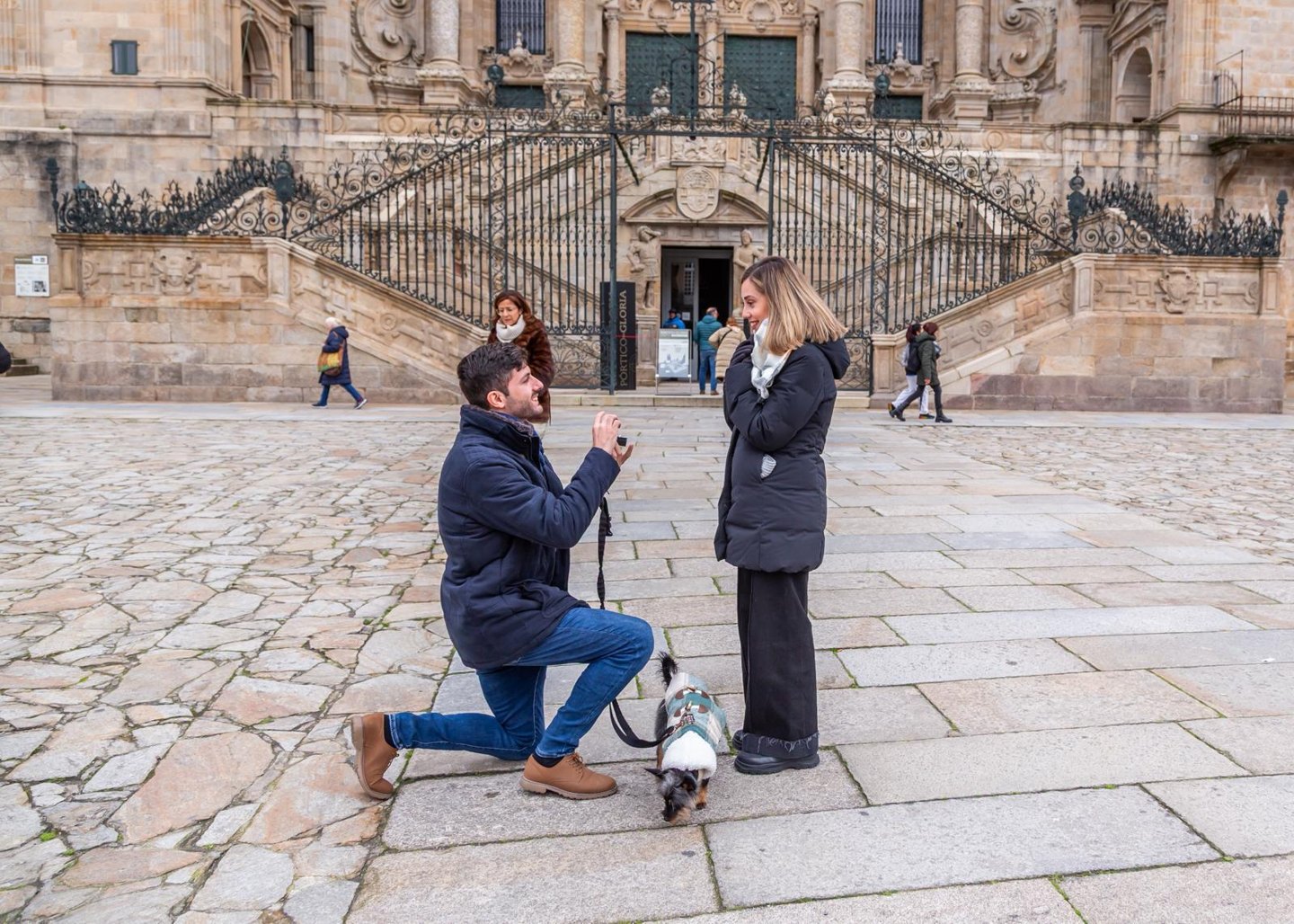 Álvaro arrodillado frente a Henar en la plaza del Obradoiro, con Kobu a sus pies